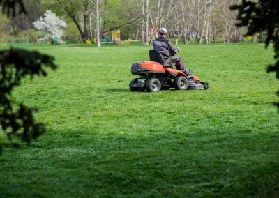 A man riding a mower and mowing a large field
