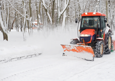A small tractor plowing snow off of a road