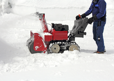 A man pushing a snow plow machine